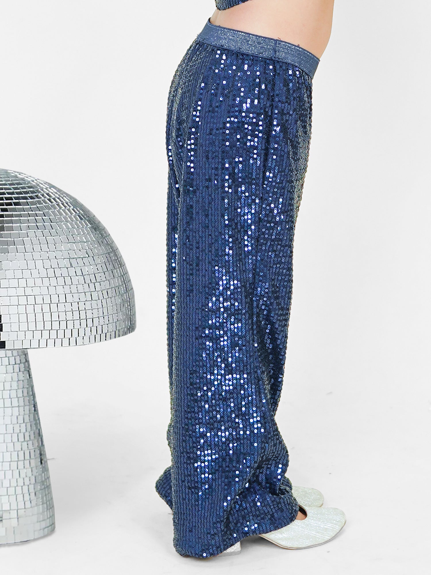 A little girl dazzles in a navy blue sequined co-ord set, featuring a chic crop top and straight pants with a glitter elastic waistband. Styled with shimmering shoes and surrounded by disco-inspired décor, this premium kids' wear ensemble is designed for a glamorous look with maximum comfort. Perfect for ages 3-14! ✨💙