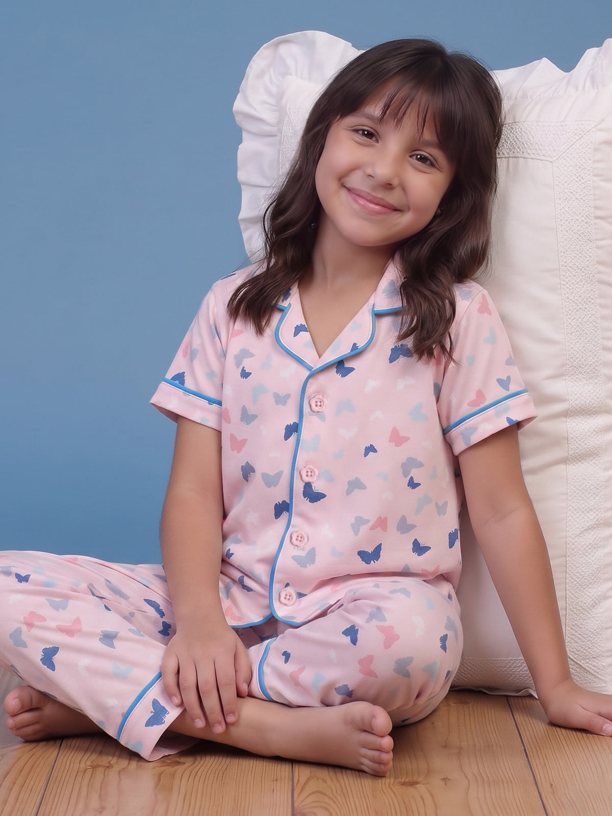 A girls sitting relaxed against pillow wearing Little Carrot Peach Butterfly Printed Night Suit