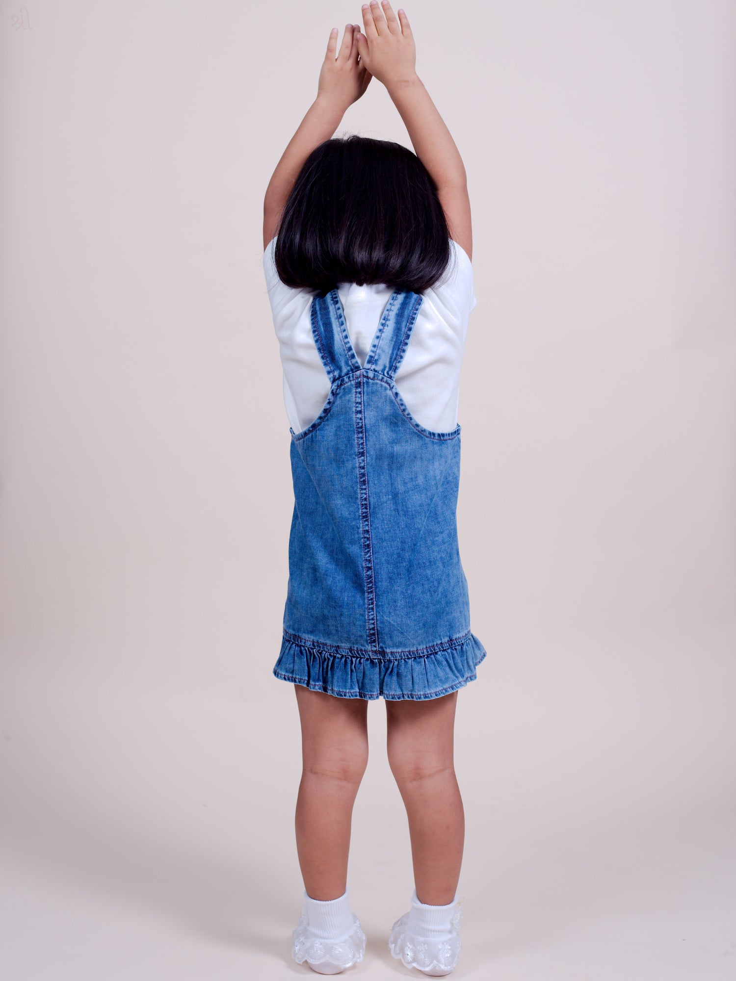 A stylish denim overall dress for infant and toddler girls, featuring floral embroidery on the front pocket, adjustable buttoned straps, and a ruffle hem for a cute and comfortable look.