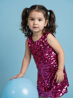 A young Girl Posing in Fuchsia Sequins Dress from Pink Skies Collection by Little Carrot