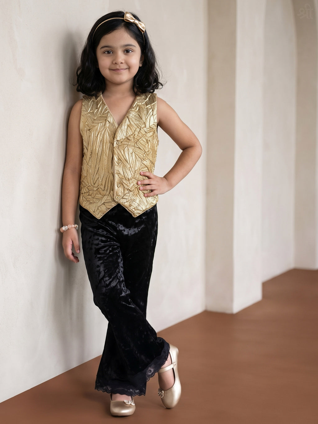 A young girl posing in Gold Vest paired with Black velvet pants from Pink Skies Collection by Little Carrot