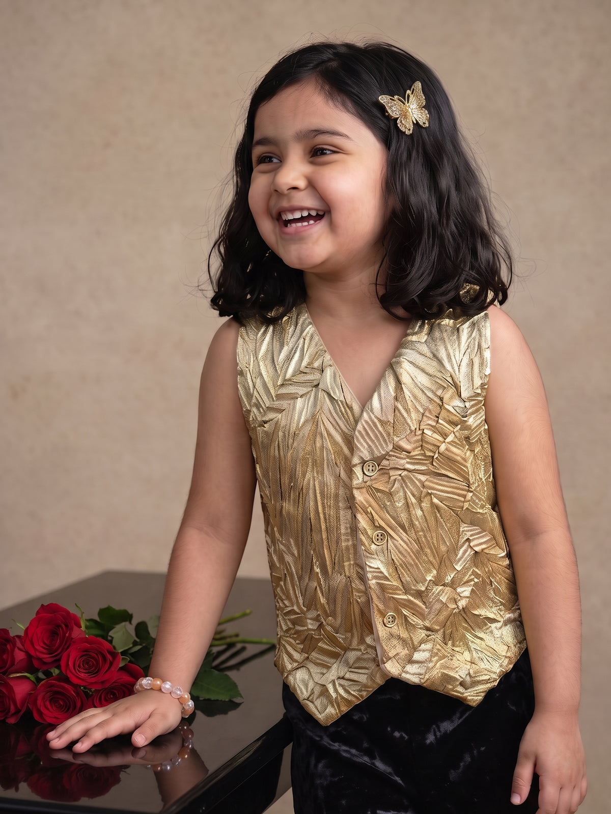 A young girl posing in Gold Vest paired with Black velvet pants from Pink Skies Collection by Little Carrot