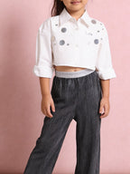 Young girl wearing a Little Carrot white cropped Shirt with Sequins Hilights paired with Silver Foil Printed Black Bottoms.