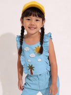 Child wearing a blue Little Carrot outfit with a sun and cloud handmade crochet patches, standing against a plain background