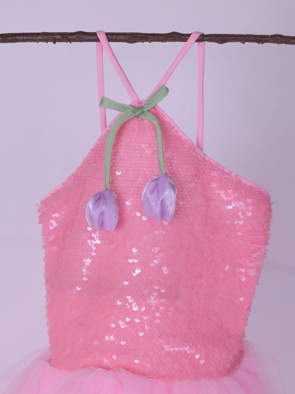 Pink sequin dress with tulip decorations on a branch against a light purple background