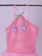 Pink sequin dress with tulip decorations on a branch against a light purple background