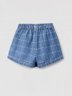 A pair of blue denim skorts with a white windowpane plaid pattern, featuring an elastic waistband, photographed flat on a light gray background.