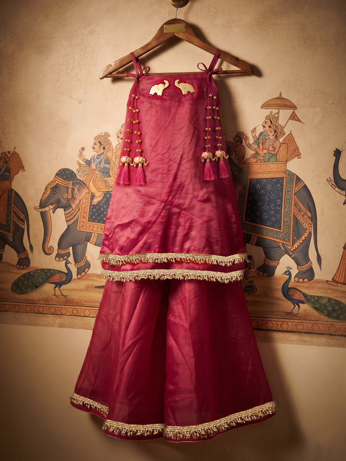 A young girl posing in Little Carrot Kurti Palazzo Set with elephant and ghungroo Detailing