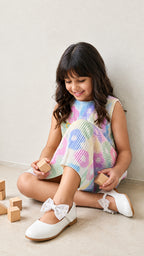 A young girl happily posing in Pastel Floal Dress from Pink Skies Collection by Little Carrot