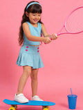Young girl in little carrot tennis outfit with pink racket on pink background, playing with skate board 