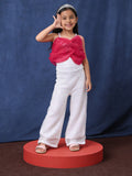 Young girl in a little carrot white sequins jumpsuit with a tiara, standing on a red platform against a blue background.