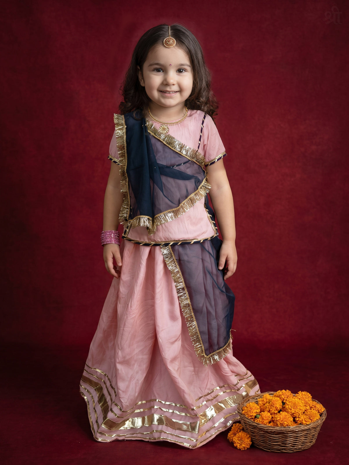 A young Girl posing in Baby Pink rajputi poshakh with contrast navy blue dupatta from Pink Skies collection by Little Carrot