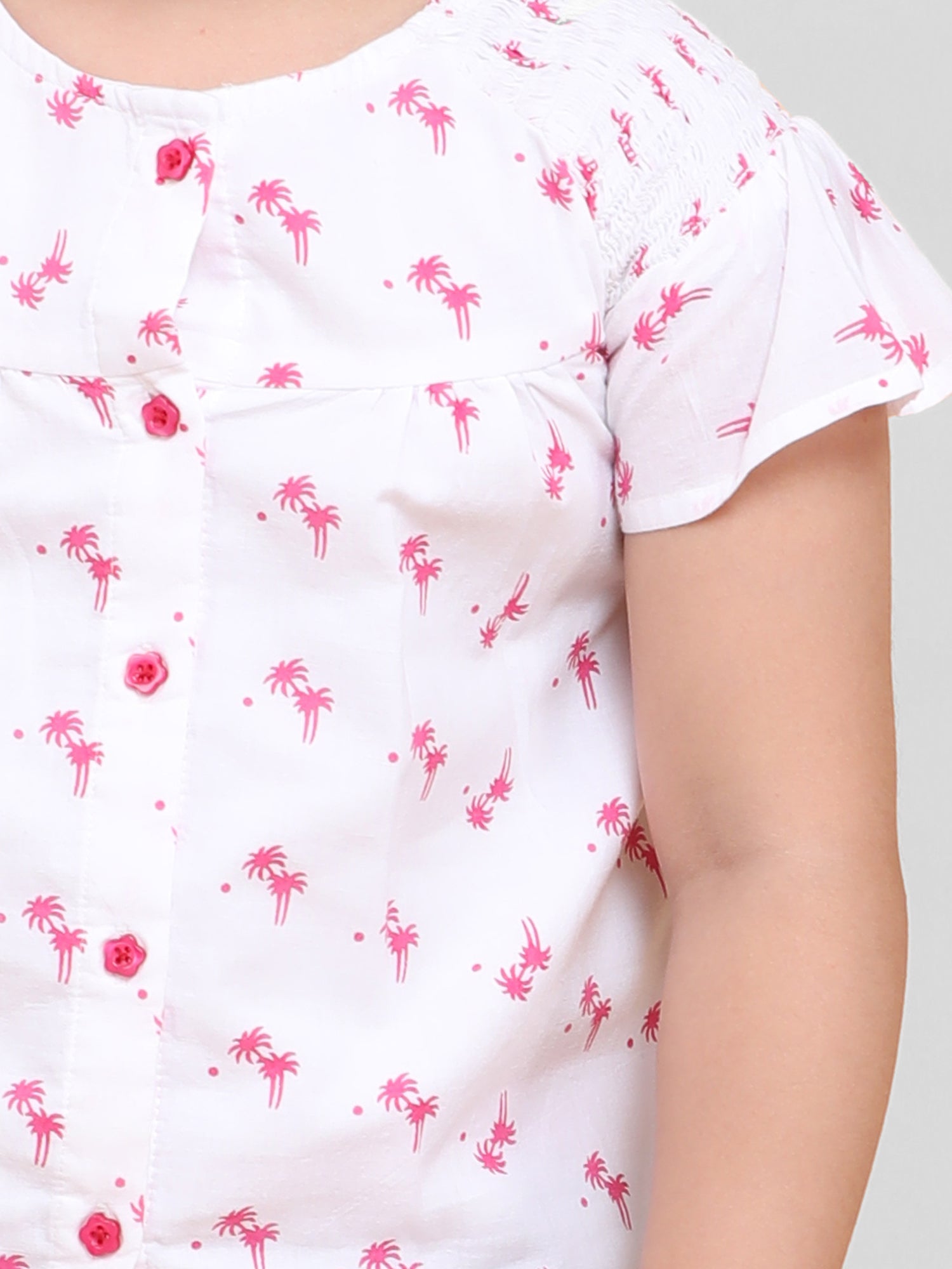 Little girl wearing a white cotton co-ord set with pink palm tree print, perfect summer playwear outfit by Little Carrot.