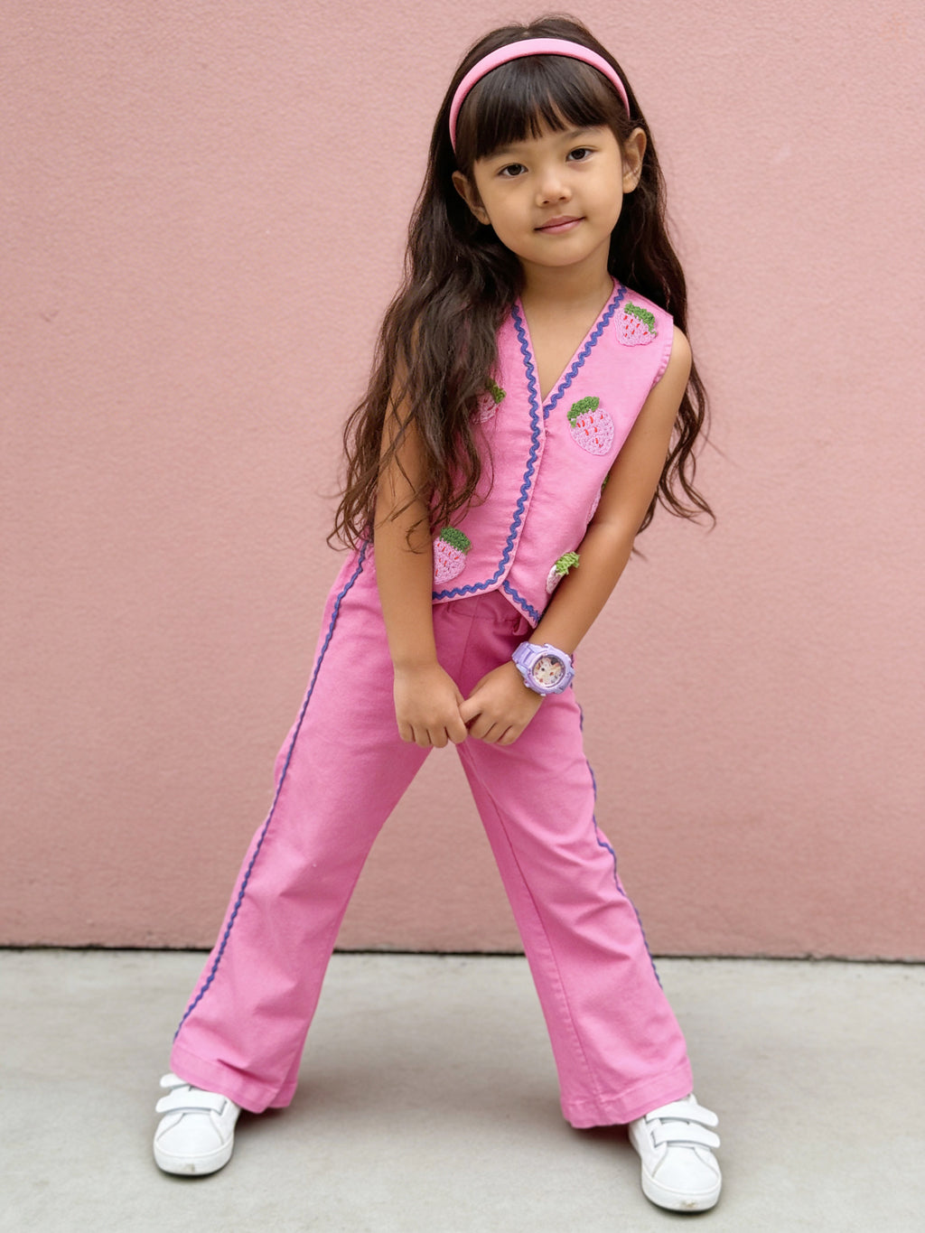 Young girl in a pink Little Carrot outfit standing against a pink wall