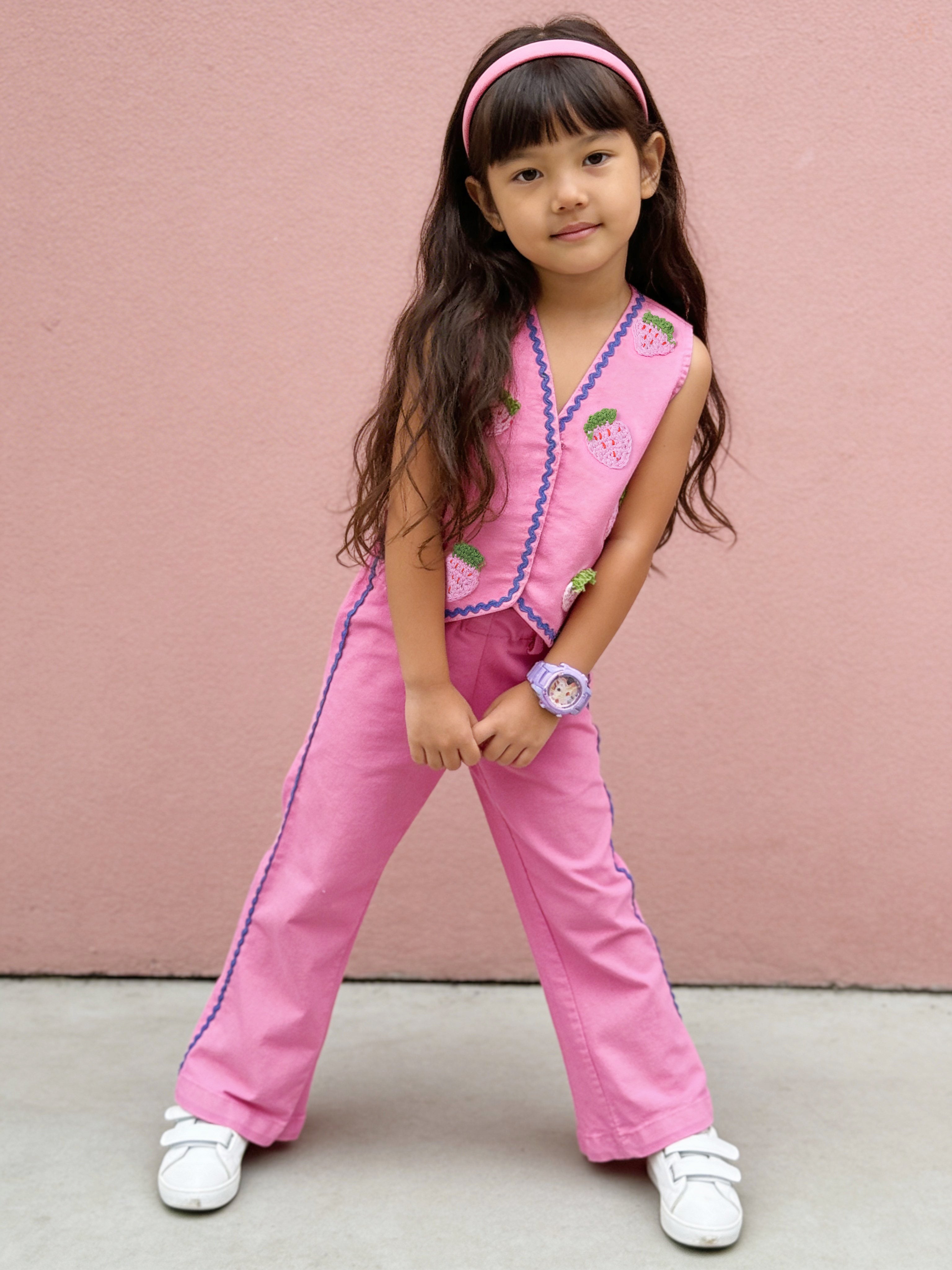 Young girl in a pink Little Carrot outfit standing against a pink wall