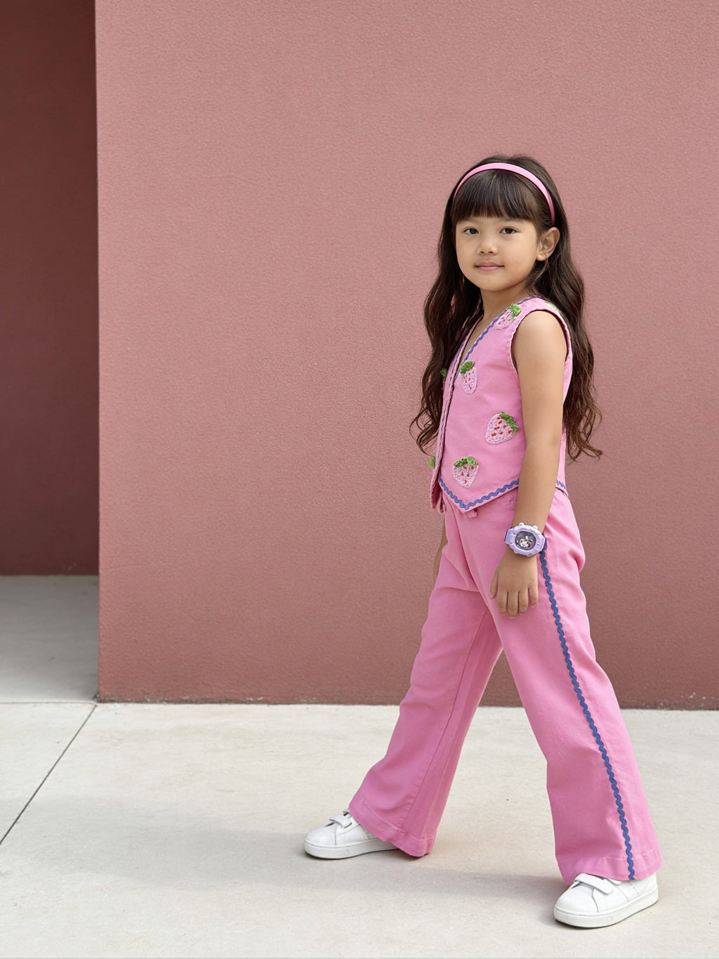 Young girl in a pink Little Carrot outfit standing against a pink wall