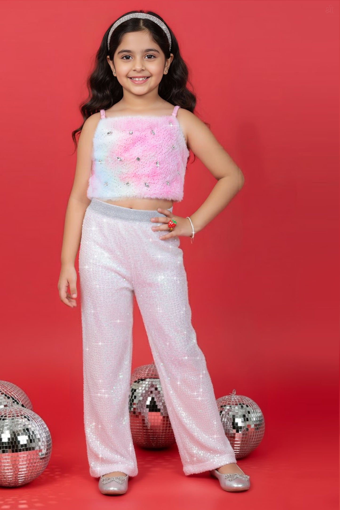 A Girl wearing a Little Carrot Partywear Fur top and white sequin pants on a red background with disco balls.