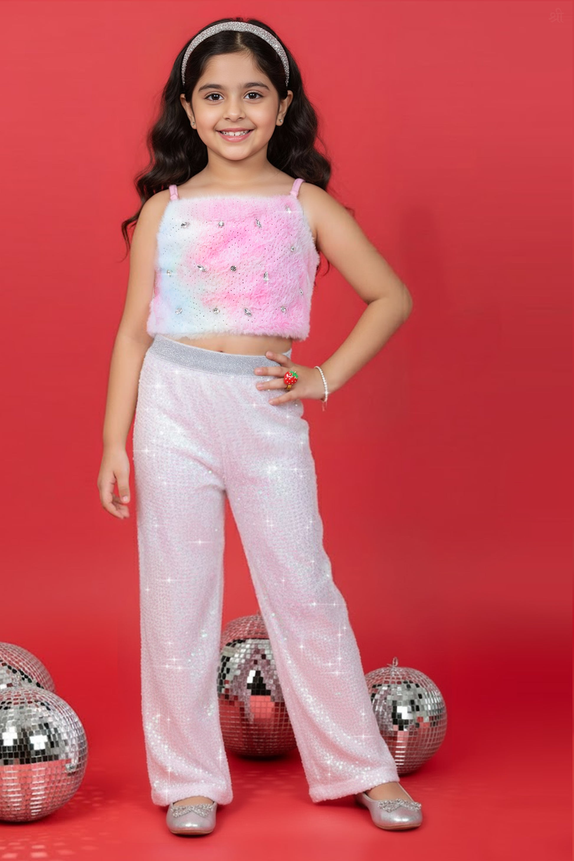A Girl wearing a Little Carrot Partywear Fur top and white sequin pants on a red background with disco balls.