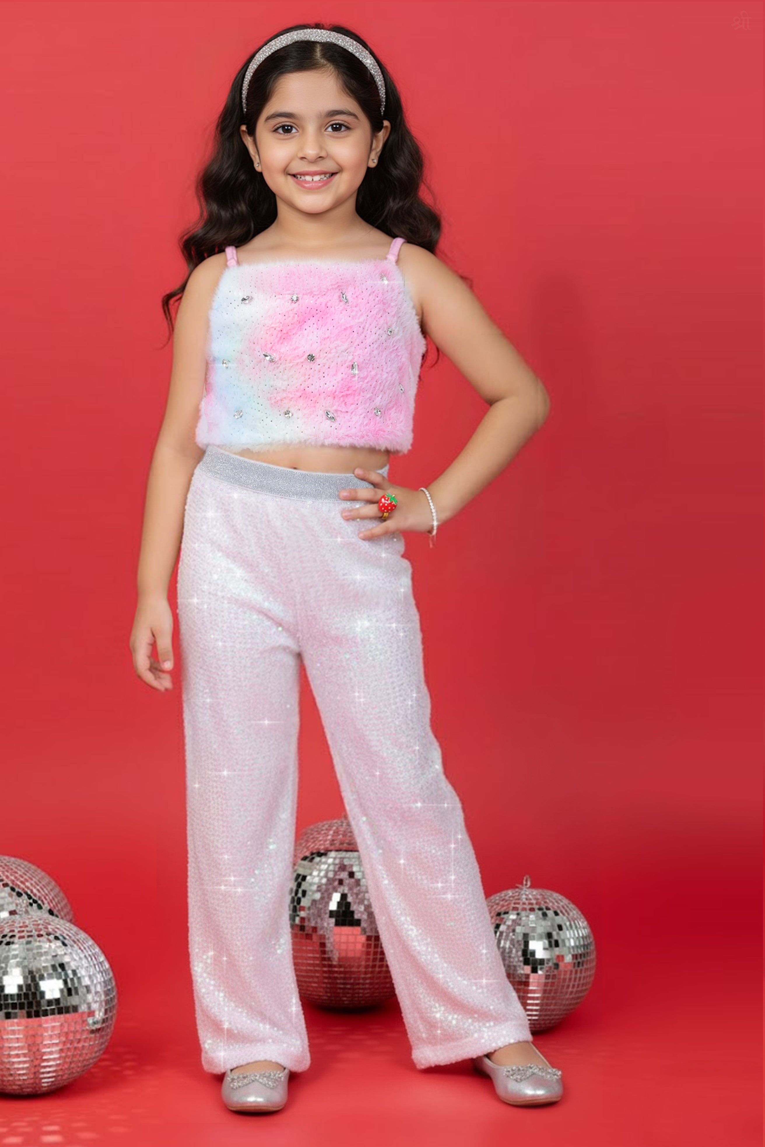 A Girl wearing a Little Carrot Partywear Fur top and white sequin pants on a red background with disco balls.