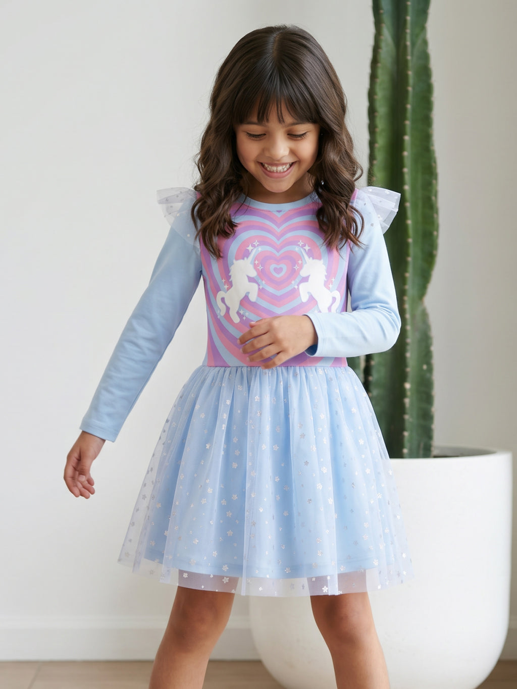 A young happy girl is posing in Little Carrot Blue Unicorn Dress