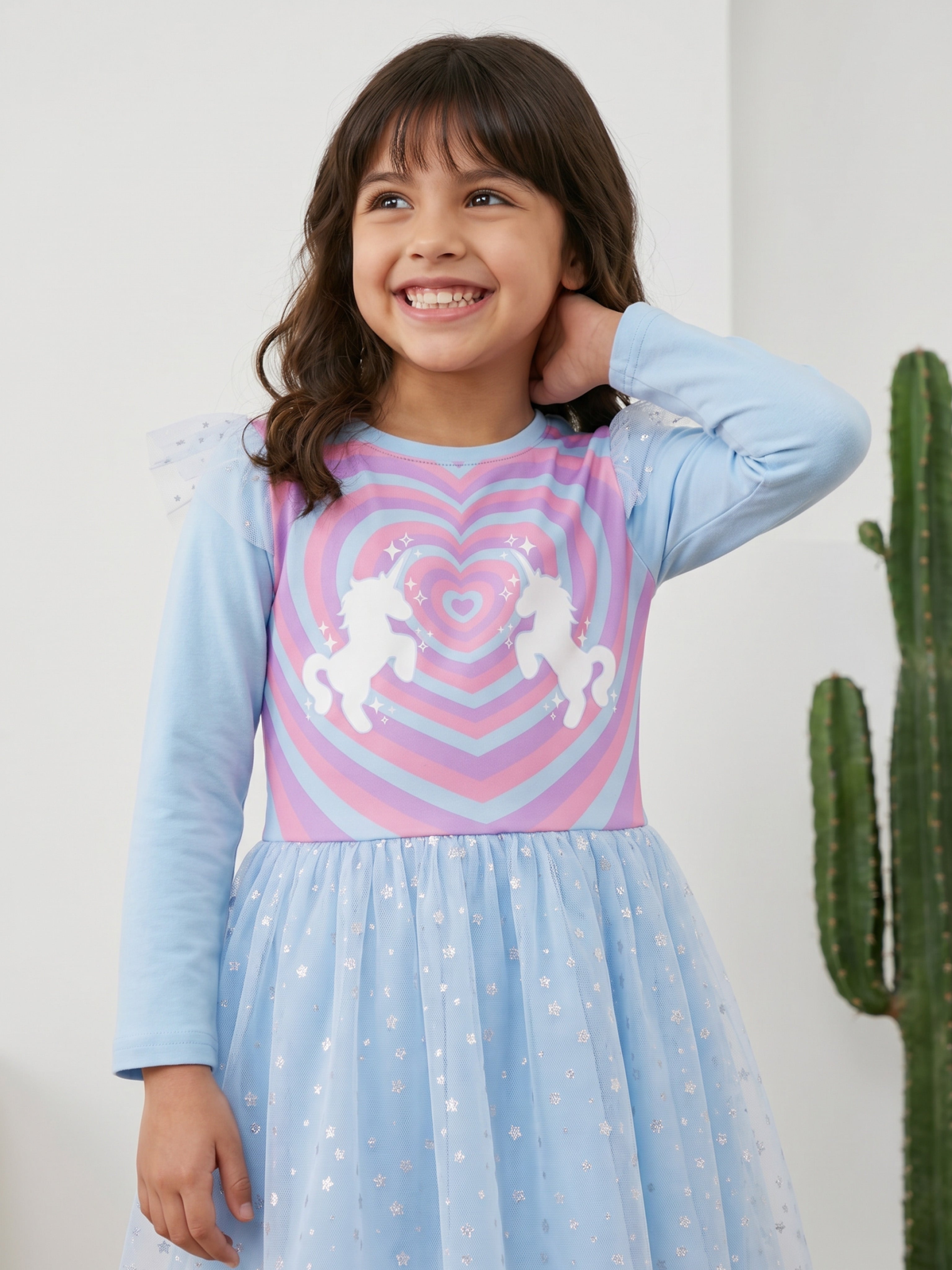 A young happy girl is posing in Little Carrot Blue Unicorn Dress